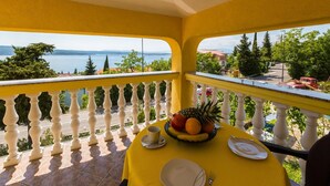 Ein Balkon mit gelbem Esstisch, der einen schönen Blick auf ein Gewässer und grüne Vegetation bietet.