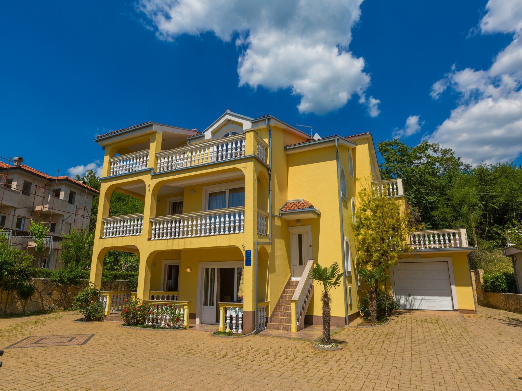 A two-story yellow building with balconies, a staircase, and a garage.
