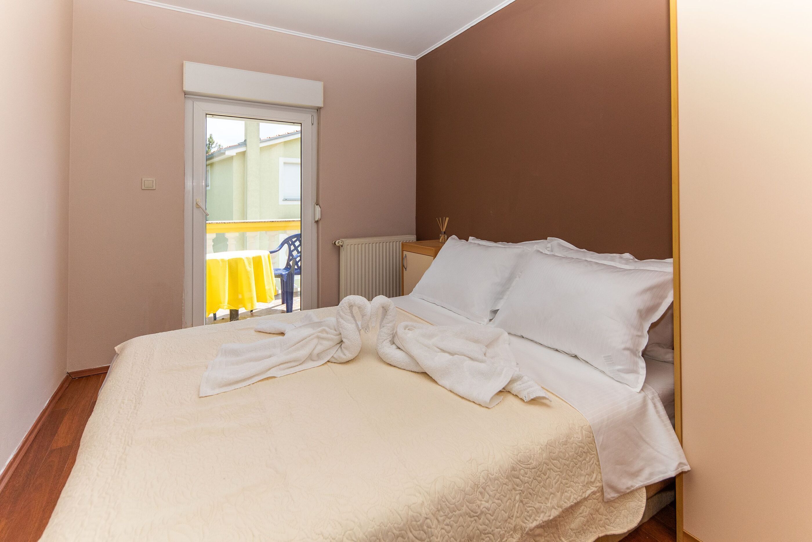 A bedroom with a bed, a radiator, and a door leading to an outdoor area.