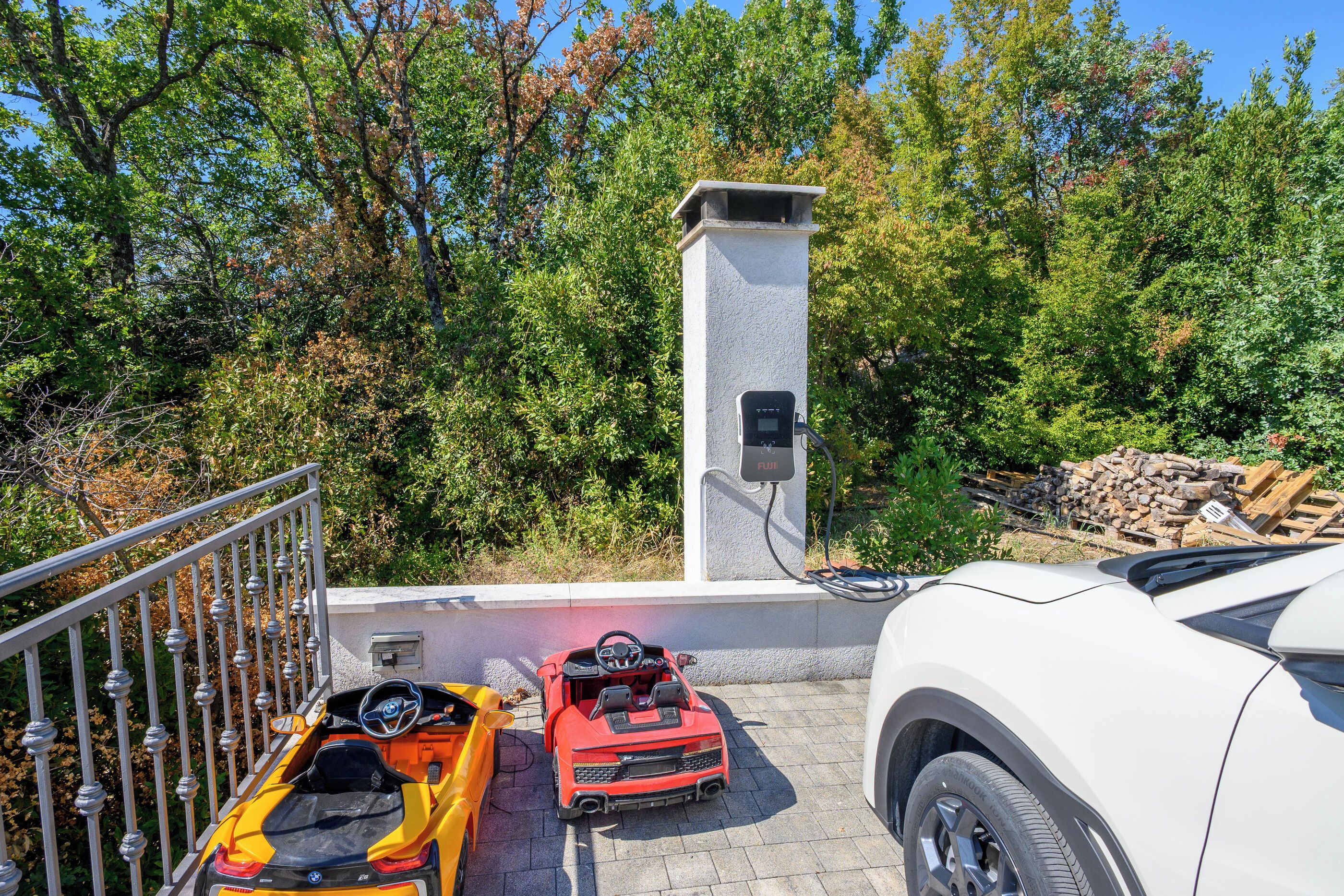 A parking area with electric vehicle charging stations, a white SUV, and a red sports car.