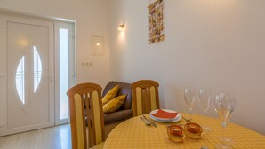 A dining area with a checkered tablecloth, a brown leather sofa, and a yellow rug. - Apartments Franco (Selce)