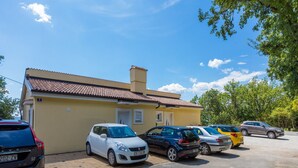 Uma área de estacionamento com vários carros estacionados em frente a um edifício amarelo com telhado em azulejos.