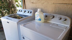 Un lave-linge et un sèche-linge à chargement frontal, avec une bouteille de lessive posée sur le dessus.