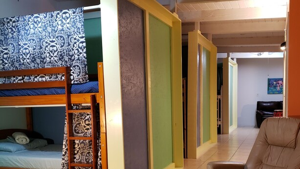 Une chambre avec un lit superposé, une chaise et un ventilateur de plafond.
