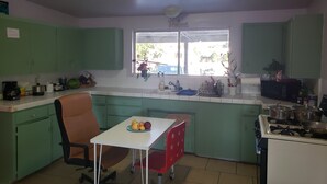 Une cuisine compacte avec des meubles de couleur verte, une table à manger avec des chaises, une fenêtre donnant sur un beau paysage et une cuisinière à gaz.