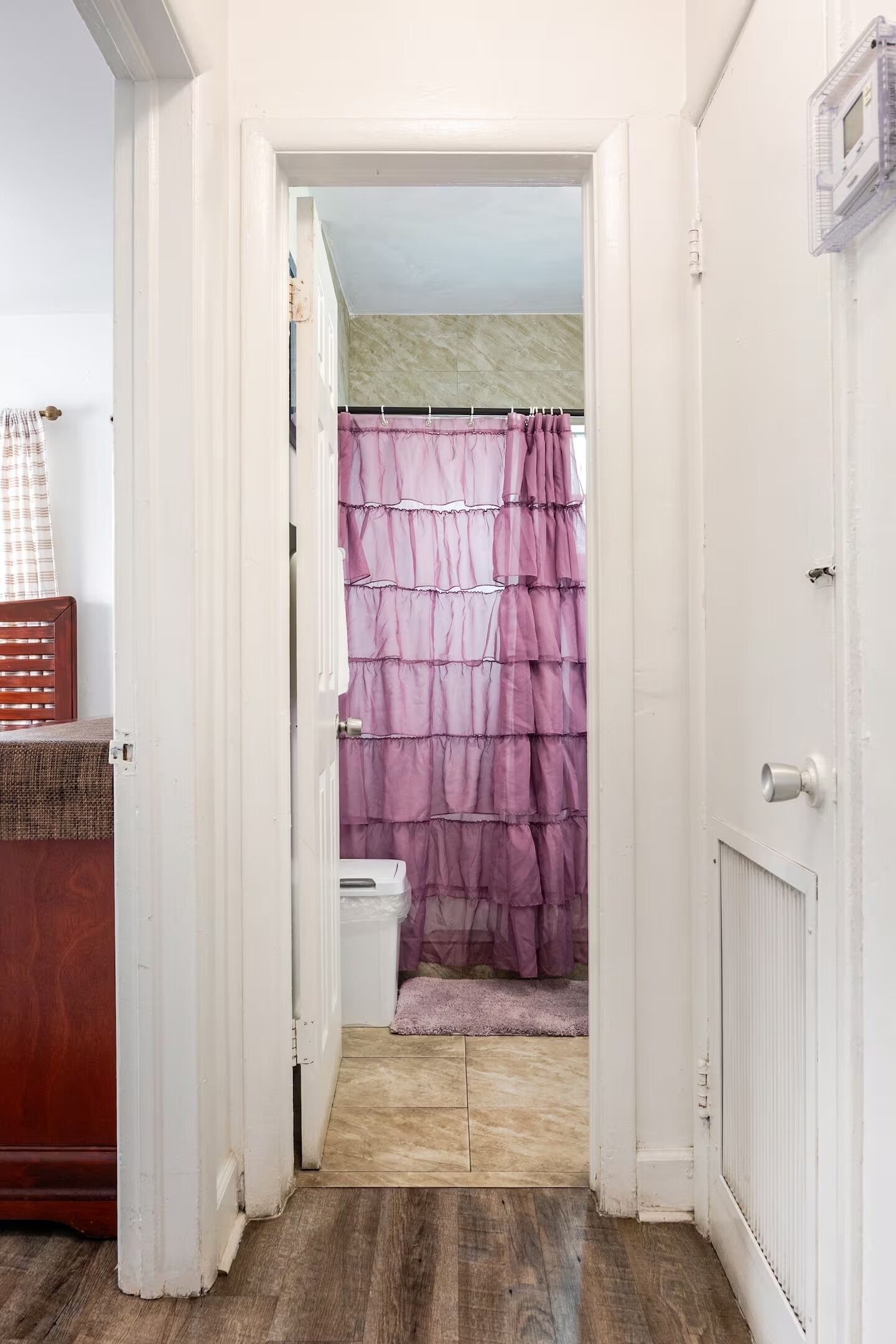 Un corridoio stretto che porta a un bagno con tenda della doccia viola.