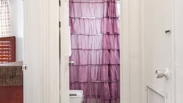 Un corridoio stretto che porta a un bagno con tenda della doccia viola.