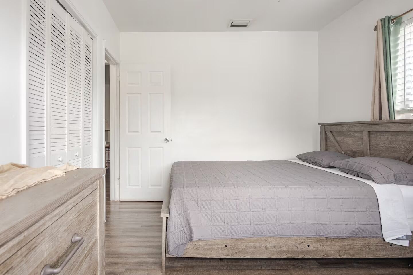A bedroom with a wooden bed, a dresser, and a white door.