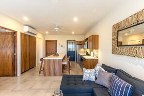 A modern kitchen with wooden cabinets, a central island, and a dining area. - Modern condo w/ private terrace and plunge pool (Huatulco)
