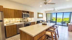 Una cocina moderna con armarios de madera, una isla central y vistas al exterior gracias a grandes puertas correderas.