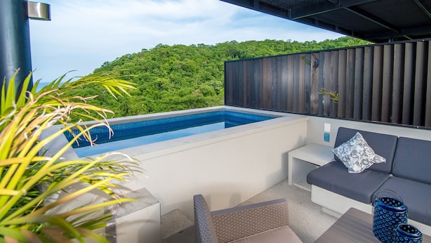Un área de piscina exterior moderna con vistas a vegetación exuberante.