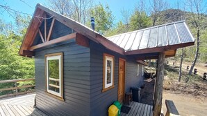 A small cabin with a wooden deck, a metal roof, and a single door. - Conguillio Park Cabin Cabin 3 people (Melipeuco)