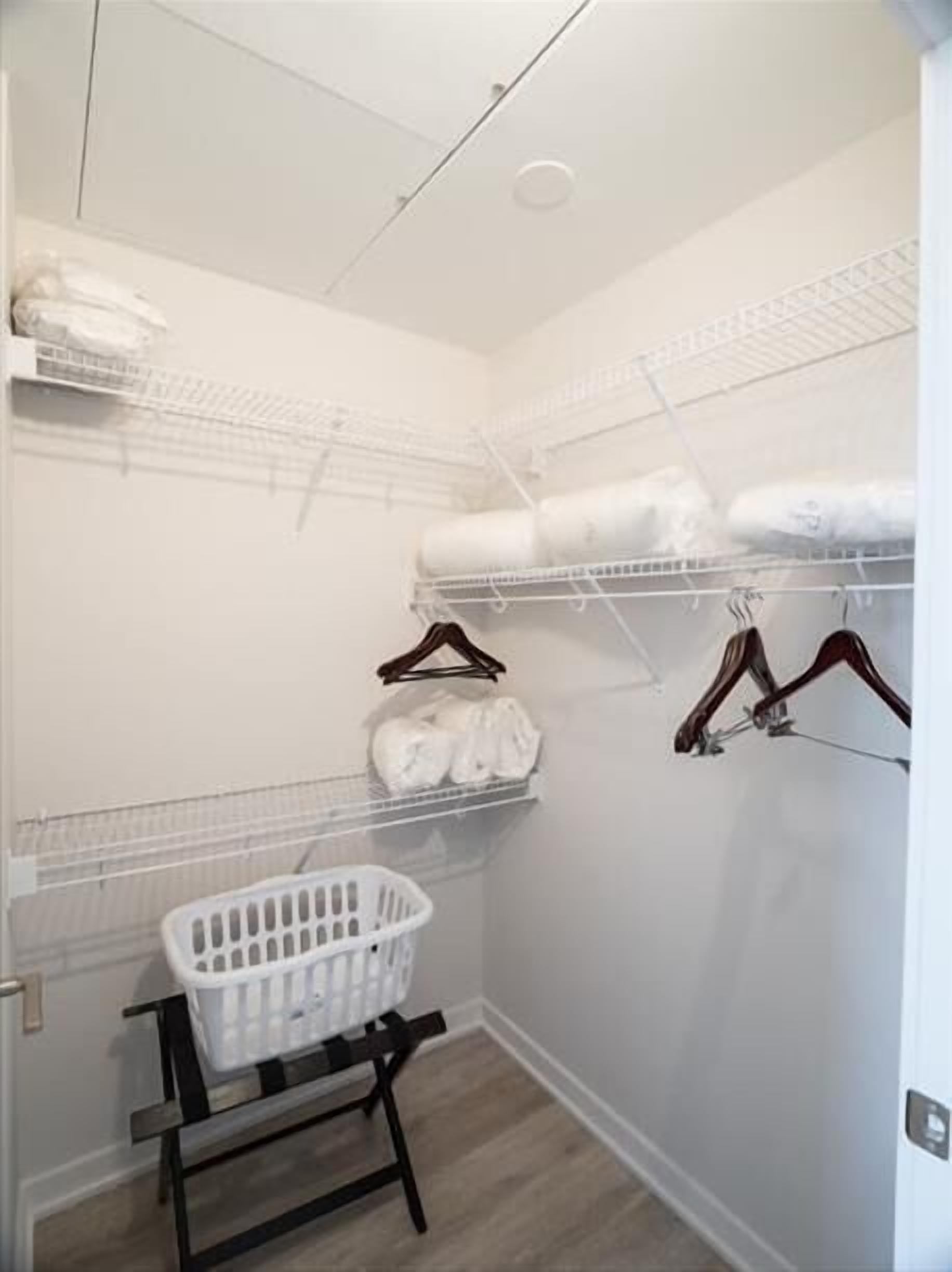 Un cuarto de lavandería con estantes para colgar ropa, un cesto de ropa sucia y un banco de madera.