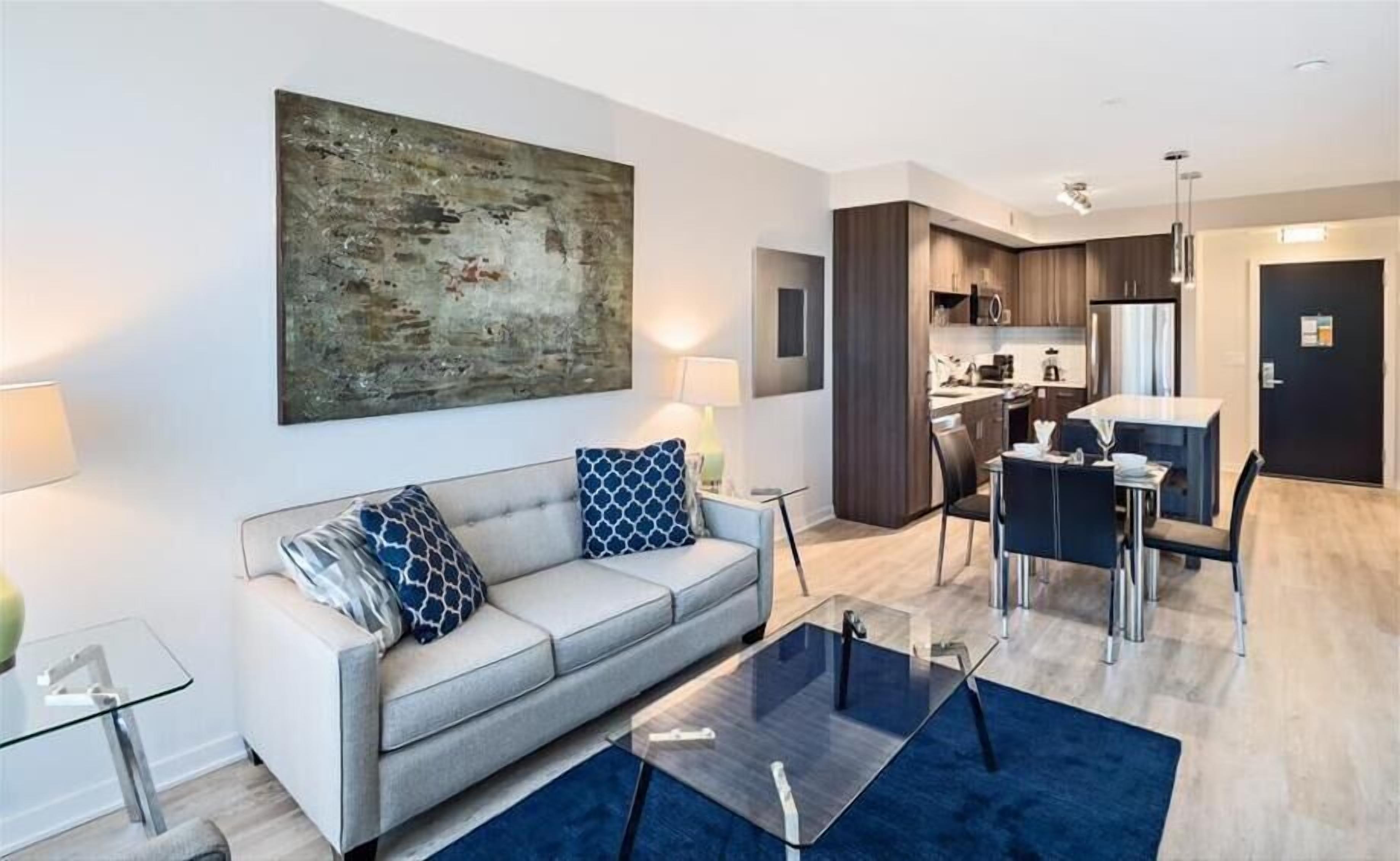 Een moderne woonkamer met een bank, salontafel en kunstwerk aan de muur.