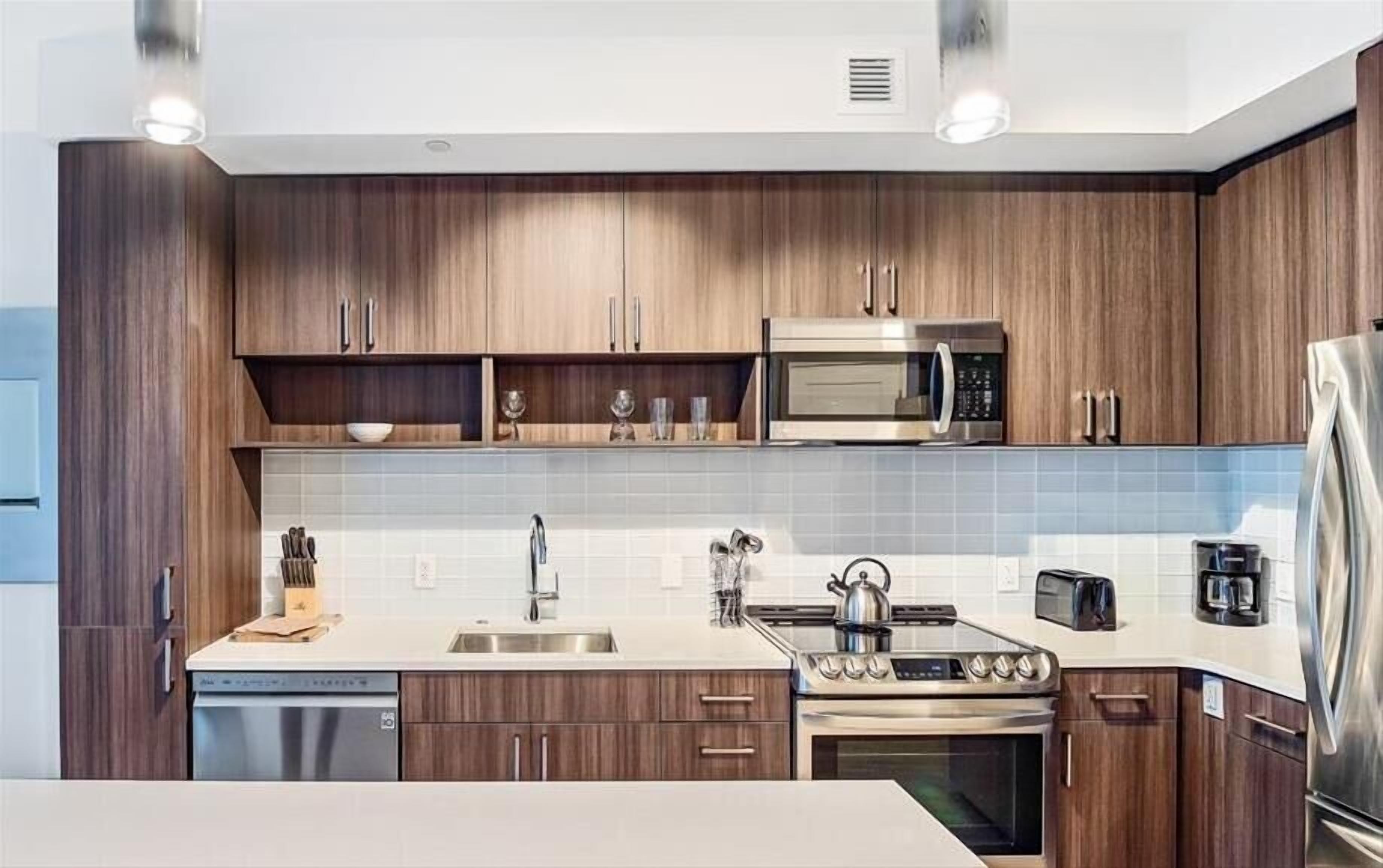 A modern kitchen with wooden cabinets, a stainless steel microwave, a stove, and a dishwasher.