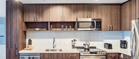 A modern kitchen with wooden cabinets, a stainless steel microwave, a stove, and a dishwasher.