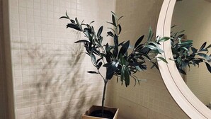 A bathroom with a potted plant, a round mirror, and a small woven basket on the counter.