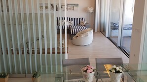 Una sala moderna con un separador de vidrio, un conjunto de sofás y una mesa de vidrio con jarrones de flores.