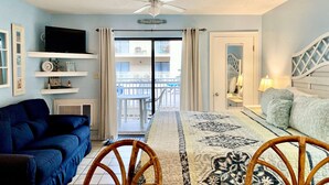 A hotel room with a balcony, a TV, a sofa, a bed, and a dining area. - Sugar Beach Condos by ALBVR (Orange Beach)
