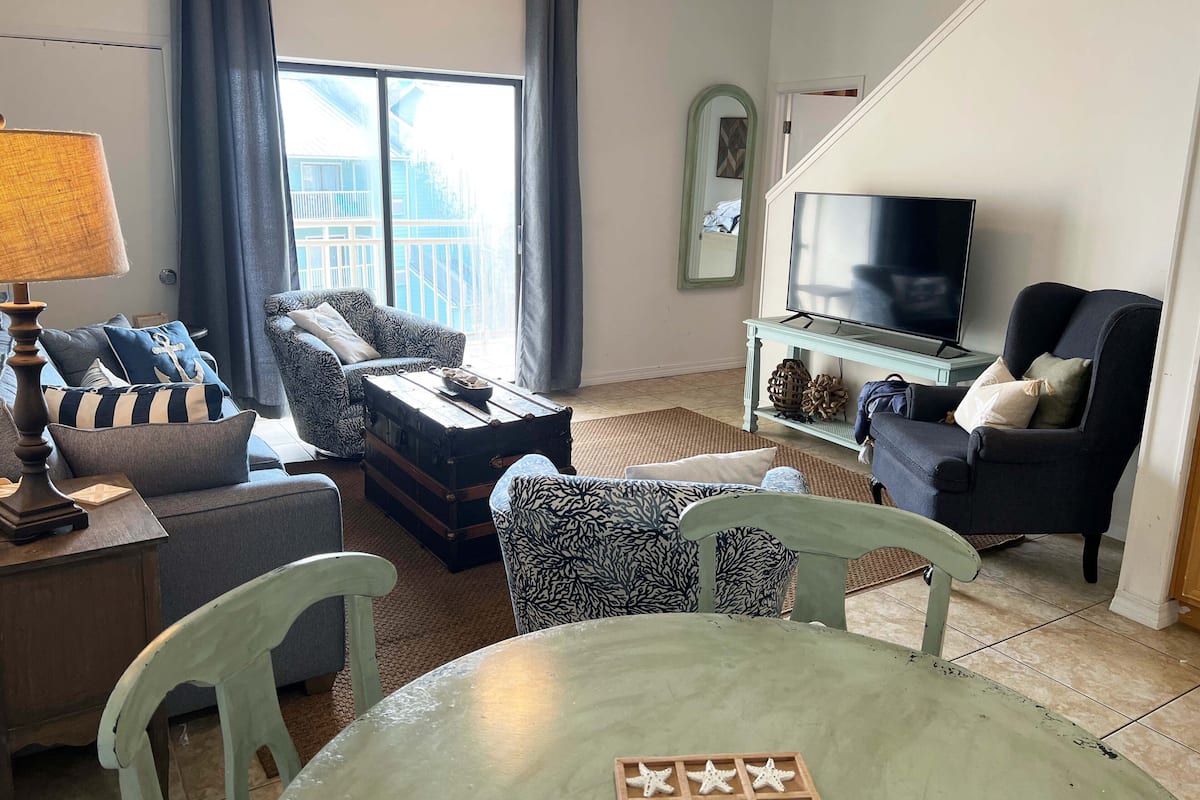 A living room with a sofa, armchairs, a coffee table, a TV, and a dining table with star-shaped cookies.