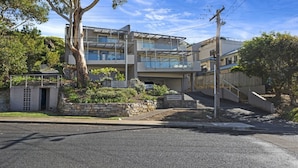 A modern two-story house with a stone retaining wall, a garage, and a staircase leading to the upper level.