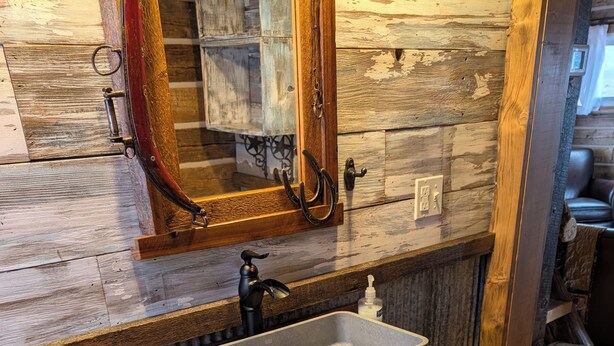 Une salle de bain rustique avec un meuble-lavabo en bois, un lavabo rectangulaire et un miroir au-dessus.