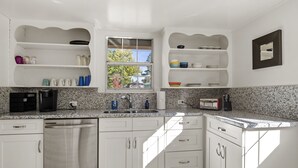 A modern kitchen with white cabinetry, granite countertops, and a built-in dishwasher. - Beaver Street Bungalow w/AC, Fenced Yard, W/D, 4 Smart TVs, 1G WiFi, RV Parking. (Flagstaff)
