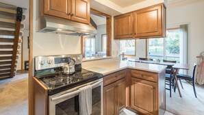 A modern kitchen with wooden cabinets, a stainless steel stove, and a large window providing natural light. - Mt Hood Escape, 3 bedroom, 2 bath, plus loft, sleeps 10, hot tub  (Mt Hood Village)