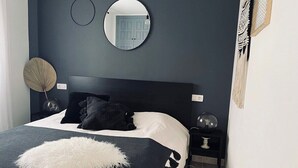 A bedroom with a bed, a round mirror, a bedside table, and a wall-mounted round mirror. - Ocean view apartment (Santiago del Teide)