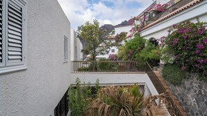 A white building with a balcony, surrounded by lush greenery and flowering plants. - Ocean view apartment (Santiago del Teide)