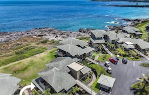 Ein Luftbild von Kapalua Bay Villas 35G1, das eine Gruppe moderner Villen mit geneigten Dächern, einen Parkbereich und Blick auf den Ozean zeigt.
