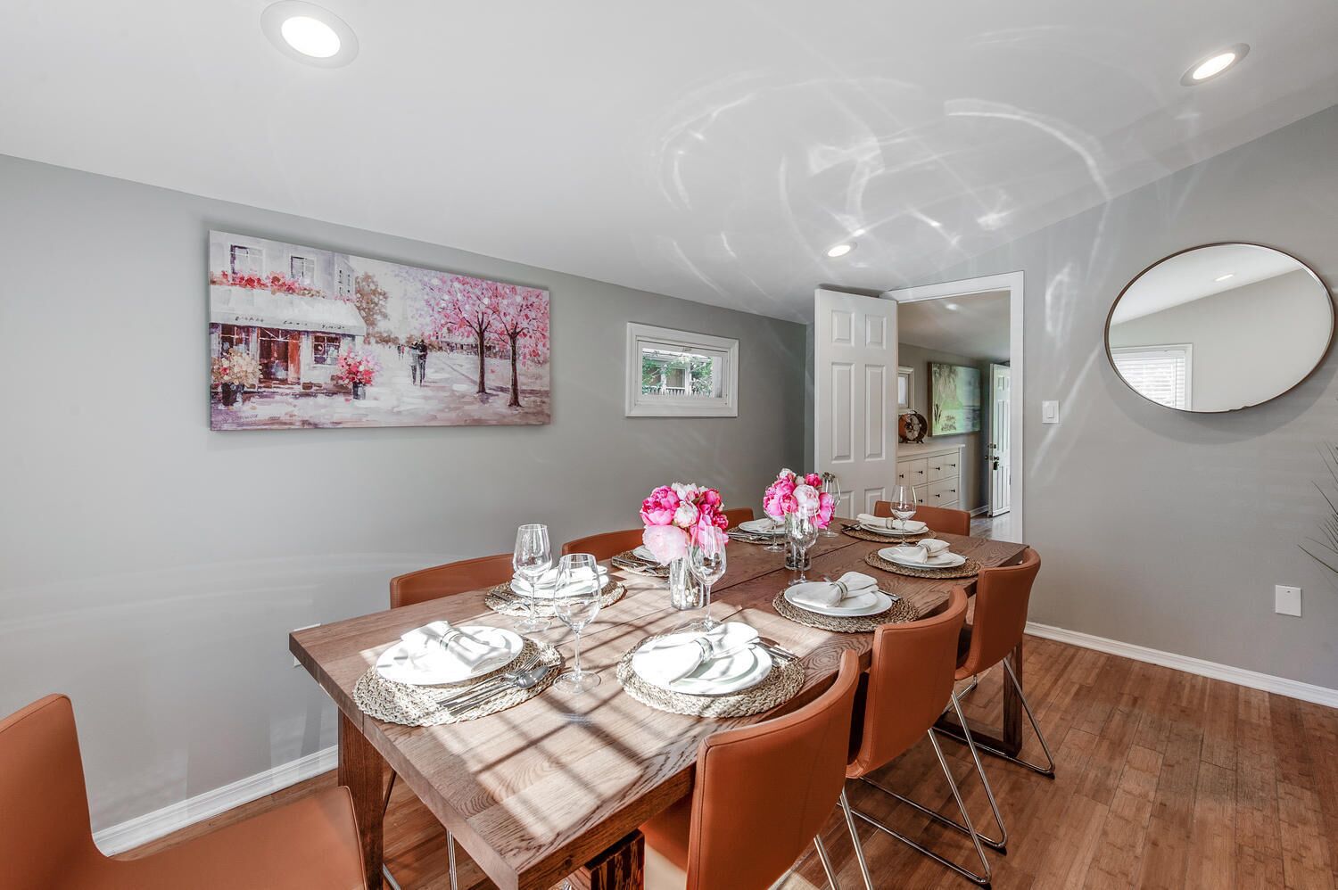 Un coin repas avec une table en bois dressée pour quatre personnes, entourée de chaises orange.