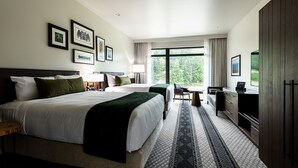 A modern hotel room with two beds, a desk, a TV, and a large window offering a view of the outdoors. - 7 Cedars Hotel & Casino (Sequim)