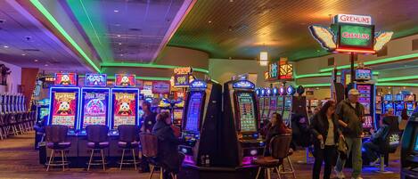 Un casino doté de nombreux appareils à sous et d’un panneau lumineux au néon représentant les « Gremlins ».