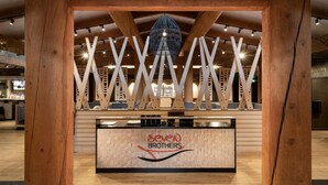 A reception area with a wooden reception desk, a logo, and a modern hanging light fixture. - 7 Cedars Hotel & Casino (Sequim)