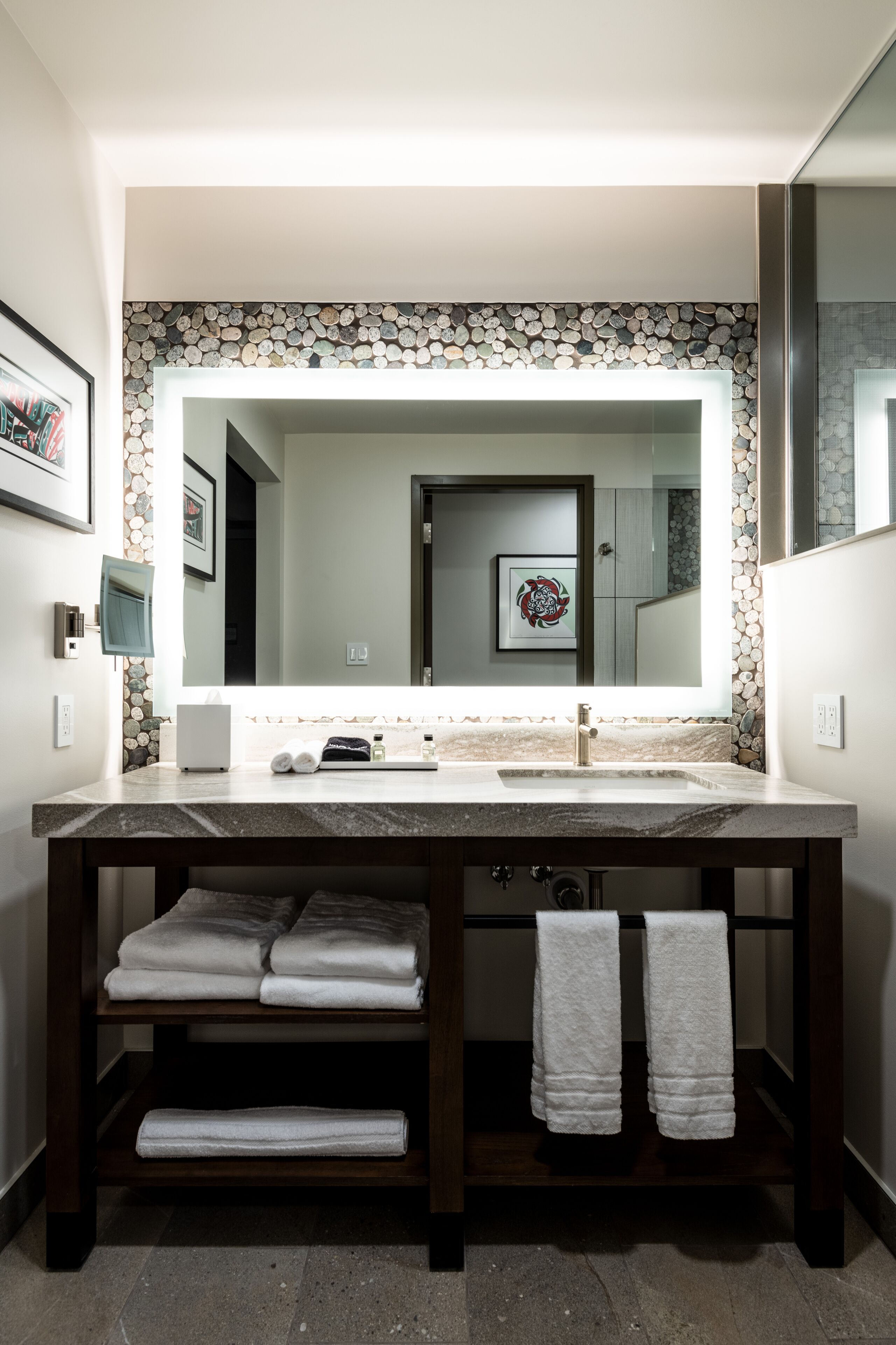 A bathroom with a large mirror, two sinks, and a towel rack.
