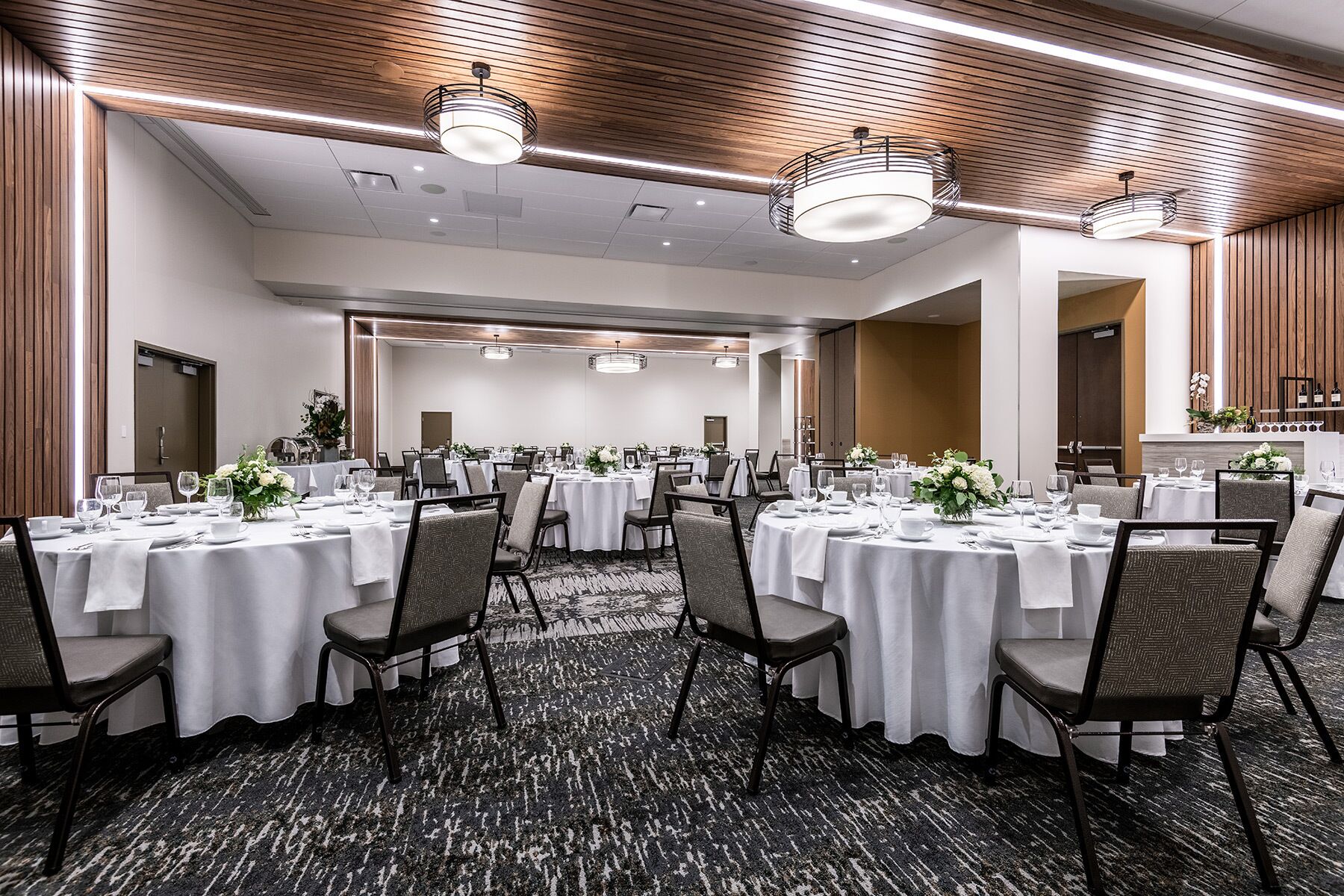 A conference room with round tables, chairs, and a carpeted floor.