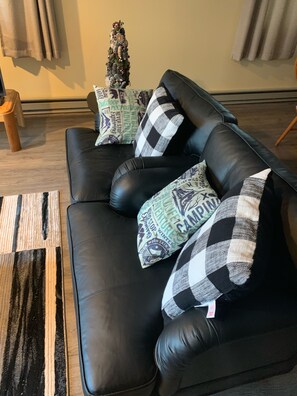 A black leather sofa with checkered pillows and a small Christmas tree. - Cozy Clean 2nd Floor Condo in Conway!!!    (Conway)