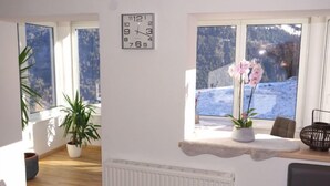 A room with a large window, a clock, a radiator, and a plant. - Wennserblick by Interhome (Wenns)