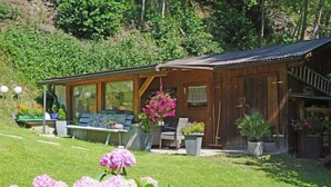 A wooden cabin with a covered porch, a bench, and potted plants. - Wennserblick by Interhome (Wenns)