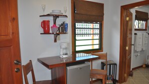 A compact kitchen with a refrigerator, a coffee maker, and a window with blinds. - Latitude 17 Garden Room, heart of Hopkins Village, Belize (Hopkins Village)