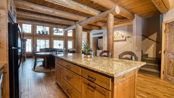 Un intérieur en bois avec un îlot de cuisine, des poutres apparentes et un coin repas.