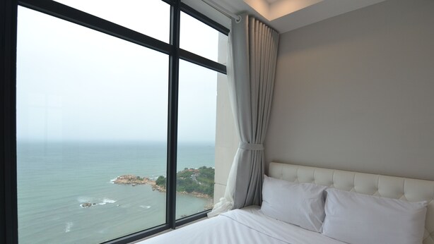 Ein Schlafzimmer mit großem Fenster, einem Bett und Meerblick.