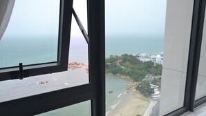 Blick aus einem Fenster auf einen Strand und eine Küstenstadt.