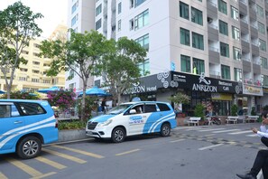 A blue and white van with a visible license plate and a hotel sign in the background. - The Crystal Apartment (Bac Nha Trang)
