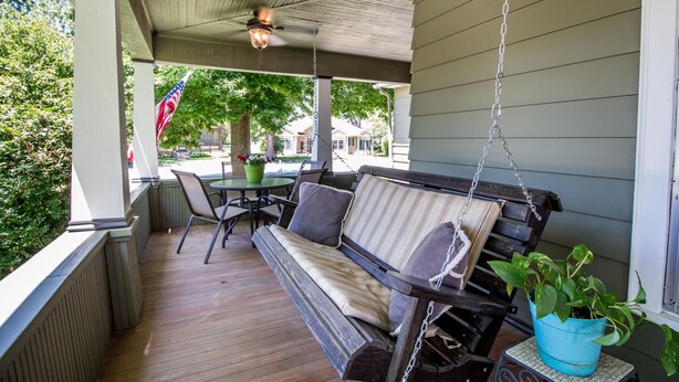 A covered porch with a wooden bench, a hanging plant, and a table with chairs. - Tastefully restored historic home in quaint town, 20 minute drive to Columbia MO (Centralia)