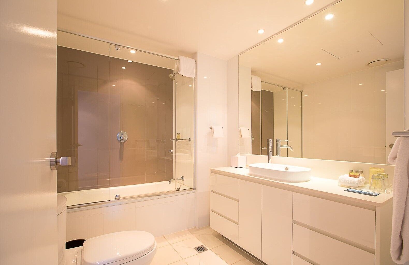 A modern bathroom with a glass-enclosed shower, a white sink, and a large mirror.