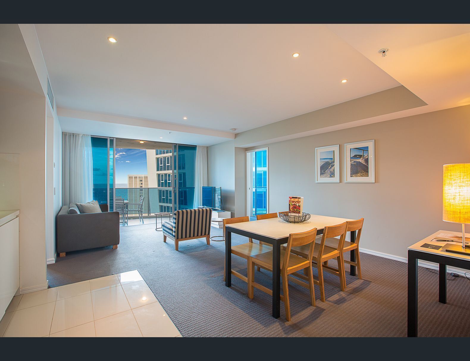 A modern hotel room with a balcony, a dining area, and a living space.