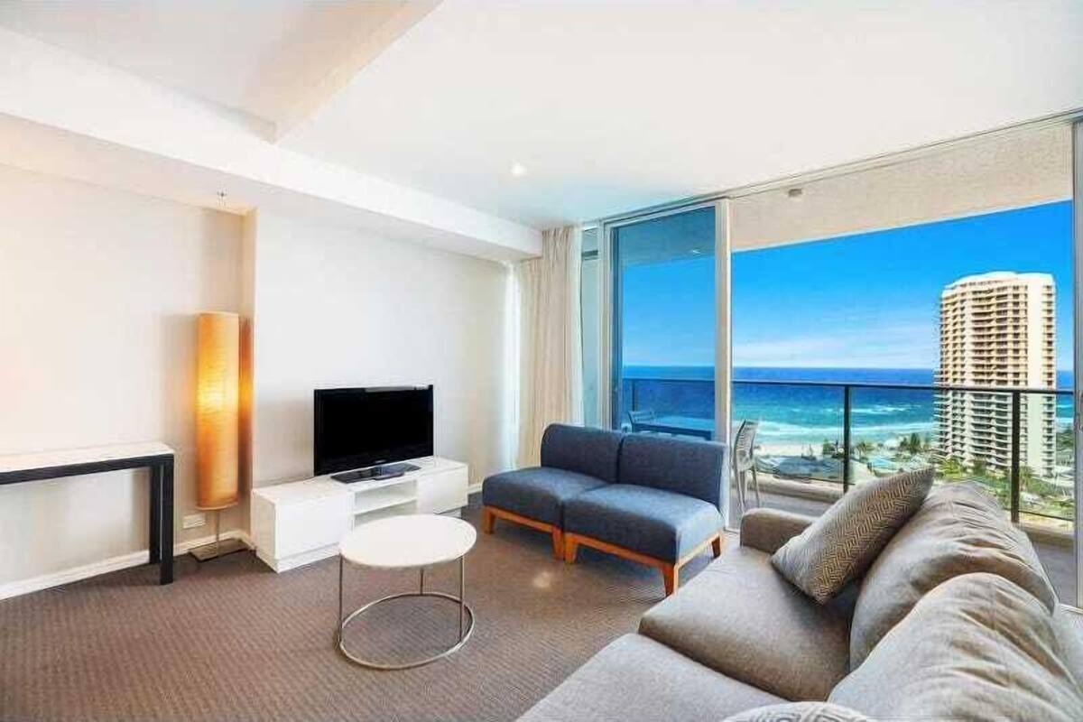 Una habitación de hotel moderna con un balcón amplio, un televisor de pantalla plana, un sofá y una mesita.