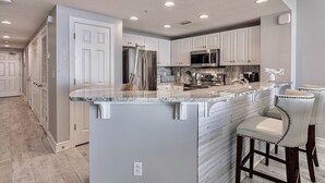 Una cocina moderna con armarios blancos, encimera de mármol y electrodomésticos de acero inoxidable.